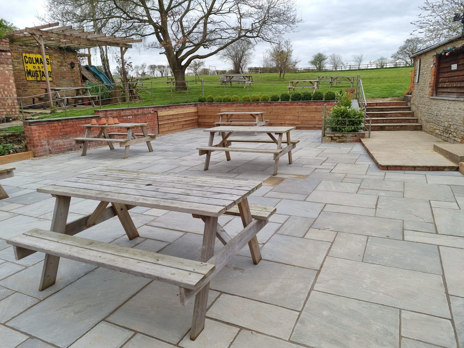 Sandstone pub garden patio with picnic benches by Boyde Landscapes.